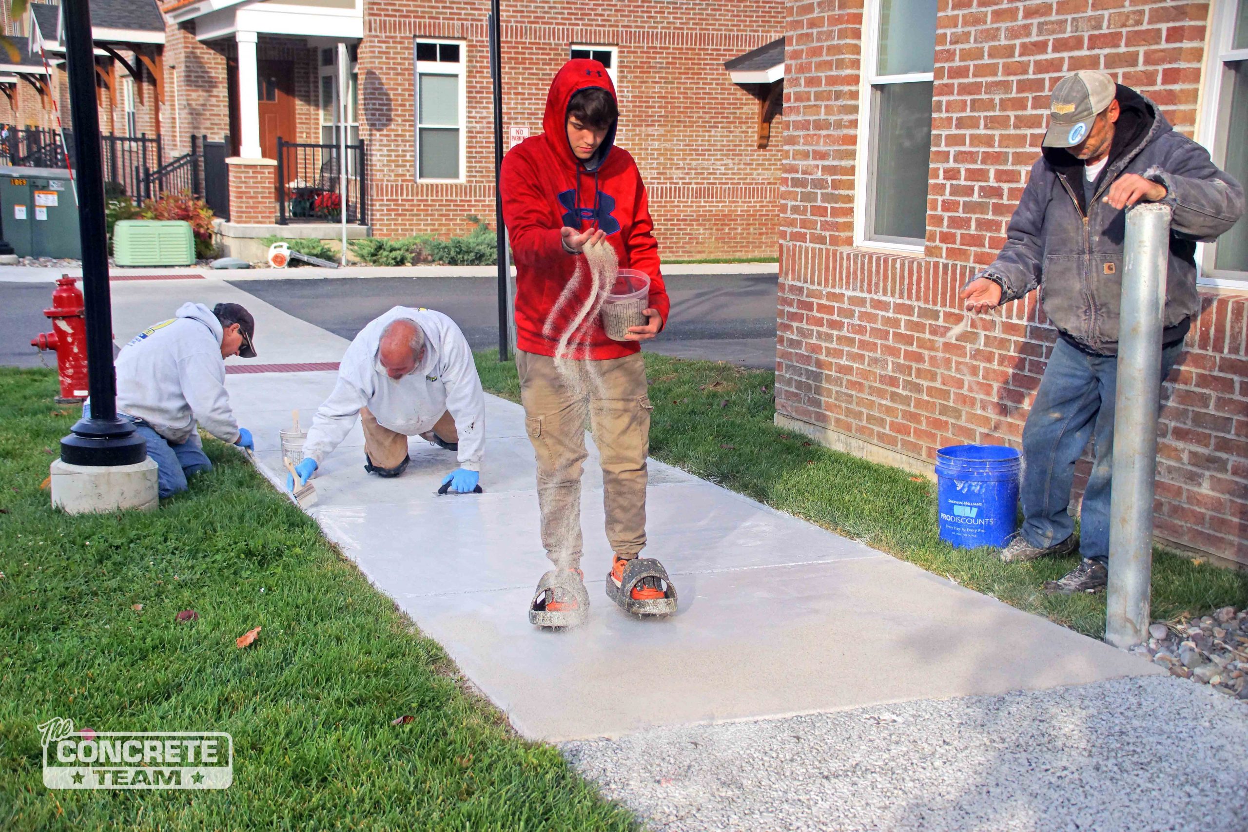 Four young men resurfacing a concrete sidewalk